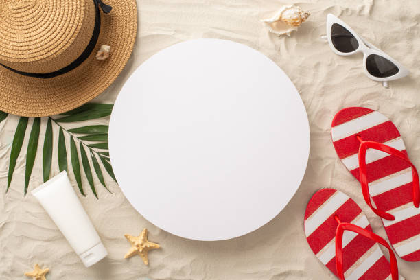 Vacation by the sea theme. Overhead shot of beach must-haves: straw hat, glasses, sandals, sunscreen, seashell, starfish, palm leaves. Sandy shore backdrop with empty circle for text or ad tema de vacaciones junto al mar. foto aérea de los imprescindibles de la playa: sombrero de paja, gafas, sandalias, protector solar, conchas marinas, estrellas de mar, hojas de palma. fondo de playa arenosa con círculo vacío para texto o anuncio
