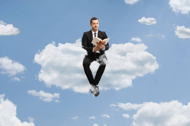 istock Businessman sitting on a cloud with a book 1495023215