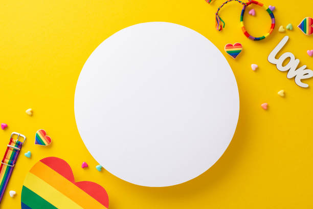 istock A top-down view of LGBT pride parade accessories, featuring a rainbow colored postal, wristlet, pin badges, hearts, and more, on a vibrant yellow background with circle for text or an advertisement 1495024238