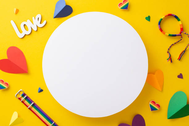 istock Vibrant yellow backdrop with top view parade accessories flat lay, including rainbow colored hearts, inscription love, wristlet, and pin badges with an empty circle for text or advert 1495024299