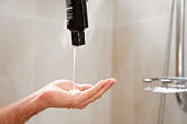 Shampoo is poured from the bottle into the palm of the hand.