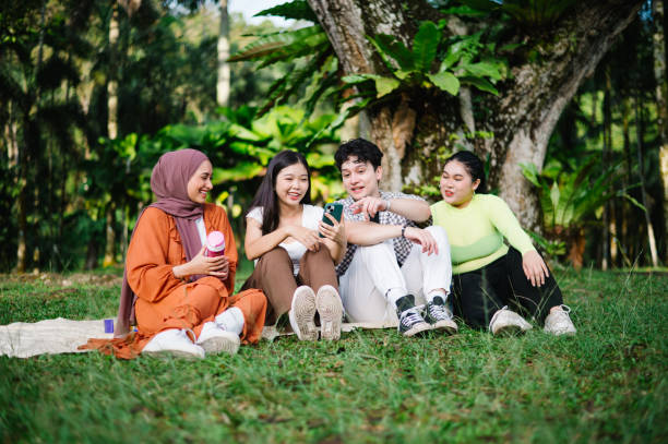 istock Multiethnic friends having fun sitting on grass outdoor. 1495025191