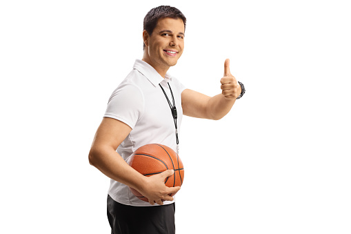 Basketball coach holding a ball and gesturing thumbs up isolated on white background