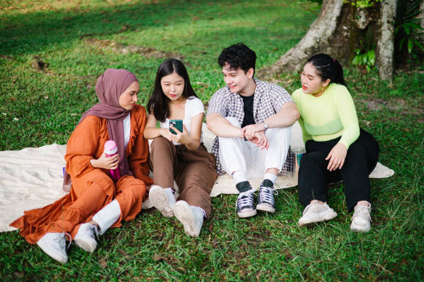 istock Multiethnic friends having fun sitting on grass outdoor. 1495025236