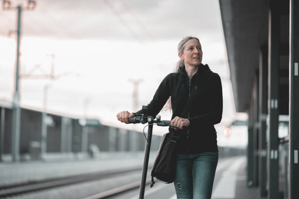 istock woman with electric scooter walking at empty railway station platform 1495025879