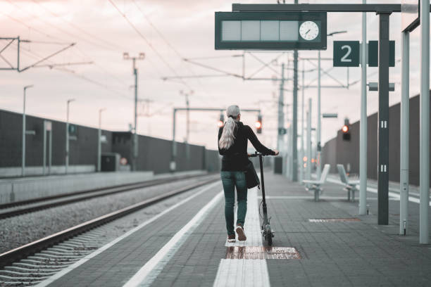 istock woman with scooter at railrod station platform, rear view 1495025893