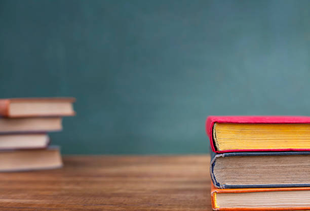 istock A stack of books on a wooden table in front of a blackboard 1495026445
