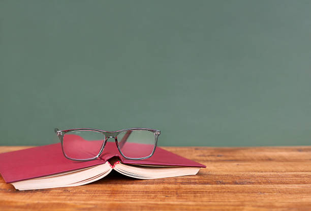 istock Open book with glasses on wooden table with copy space 1495026472