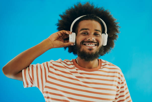 istock Afro-haired young black man standing and looking into the camera while holding headphones and listening to music. Stock image 1495026656