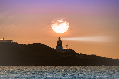 At dusk, the sun goes towards the horizon, the silhouette of the lighthouse. Fugui Cape Lighthouse is known for its sunset shots and tourist attractions.