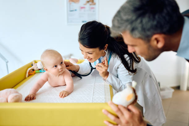 istock Cute baby looking at her father during check up at pediatrician's office. 1495030577