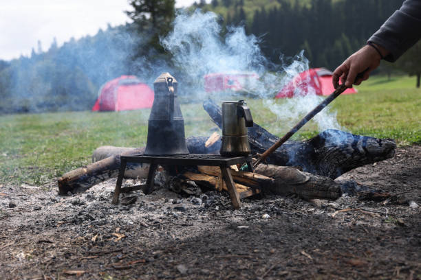 Close-up on hand of man warming on campfire with tent