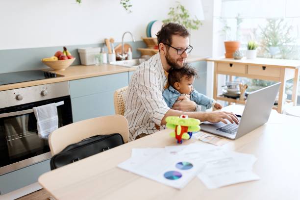 istock Man doing paperwork while taking care of his son at home 1495032414