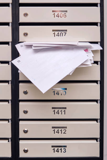 istock Mail boxes with overflowing documents and bills. Mailboxes with letters in the entrance of an apartment building 1495033553