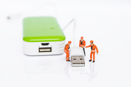 Miniature worker team with USB cable and power bank isolate on white background, energy storage,  technology industry