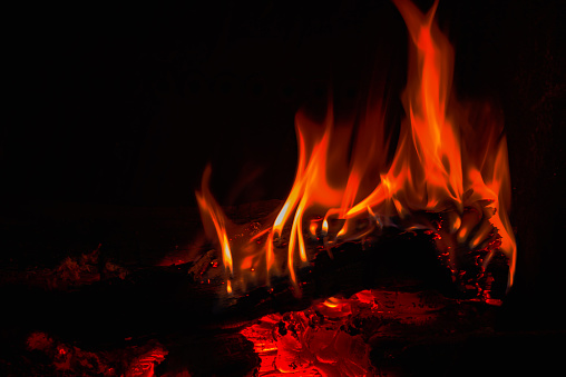 Chimney fire crackling. Flames and glowing embers on a black background