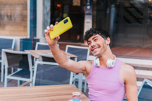 Gay man smiling confident while making selfie by mobile phone in the street