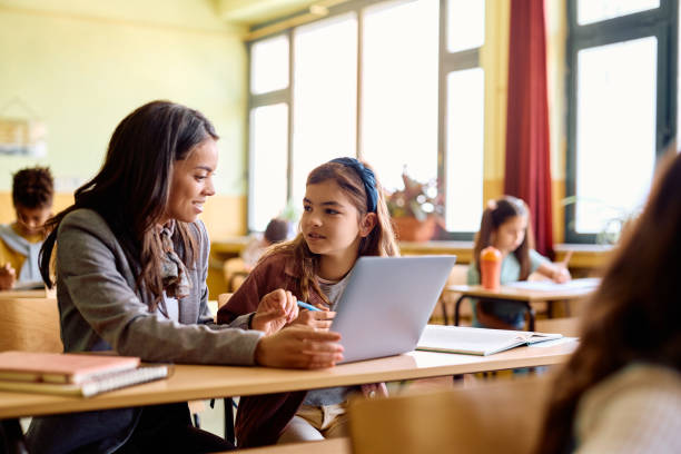 istock Happy teacher and schoolgirl using laptop during computer class in the classroom. 1495037847