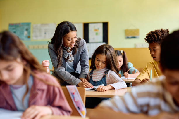 istock Happy Hispanic teacher assisting schoolgirl during a class at elementary school. 1495037853