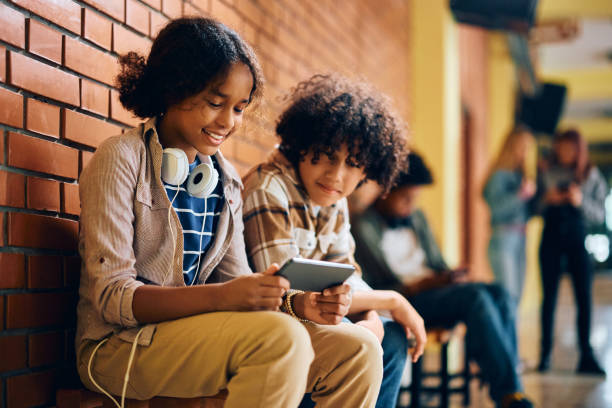 istock Happy black high school students watching something on smart phone in a hallway. 1495038146