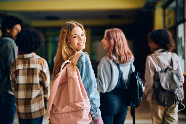 istock Happy high school student looking at camera while going on a class with her friends. 1495038182