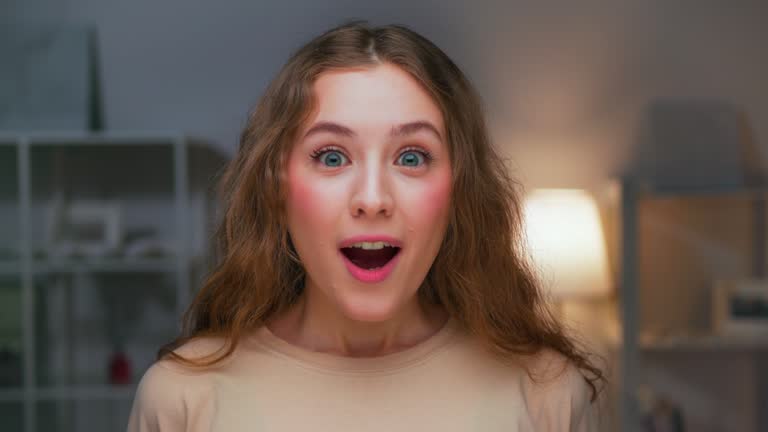 Portrait of Young Happy Woman Looking at Camera with Excited Face Close Up. Surprised Face of Female Person Watching Advertising or View of Shocking Moment. Excitement in Wondering Life of Adult Girl