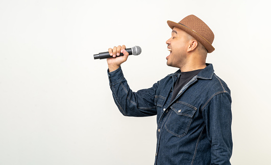 Happiness young asian man singing song. Artist vocalist singer on isolated background. Confident man public speaking talking with microphone in studio.