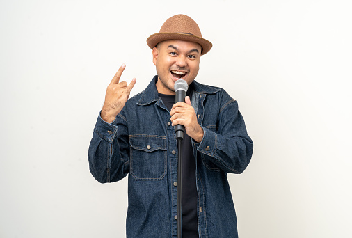 Happiness young asian man singing song. Artist vocalist singer on isolated background. Confident man public speaking talking with microphone in studio.