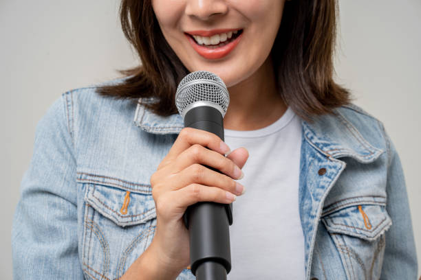 istock Close up woman hand holding High quality dynamic microphone and singing song or speaking talking with people on isolated white background. Woman testing microphone voice for interview 1495042122