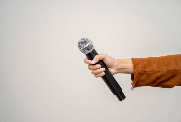 istock Close up woman hand holding High quality dynamic microphone and singing song or speaking talking with people on isolated white background. Woman testing microphone voice for interview 1495042149