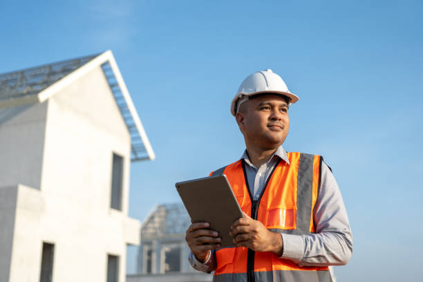 istock Confident asian engineer man Using tablet for checking and maintenance to inspection at modern home building construction. Architect working with white safety helmet in construction site 1495043297