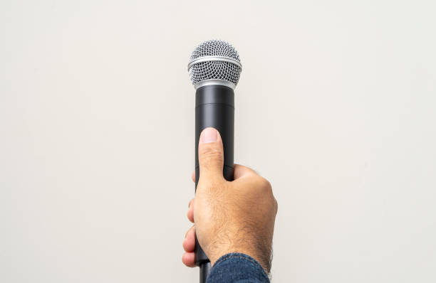 istock Close up male hand holding High quality dynamic microphone and singing song or speaking talking with people on isolated white background. Male testing microphone voice for interview 1495043540