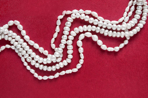 White natural pearl necklace strings on red background