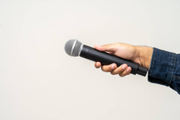 istock Close up male hand holding High quality dynamic microphone and singing song or speaking talking with people on isolated white background. Male testing microphone voice for interview 1495045098