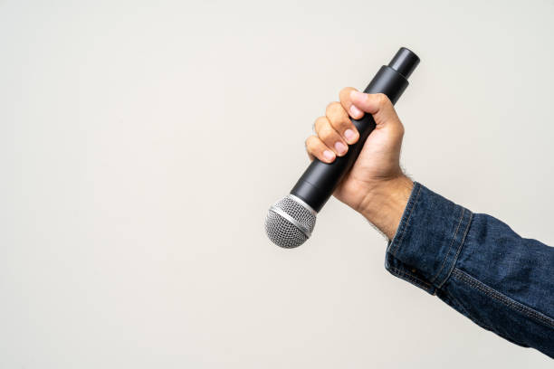 istock Close up male hand holding High quality dynamic microphone and singing song or speaking talking with people on isolated white background. Male testing microphone voice for interview 1495045445