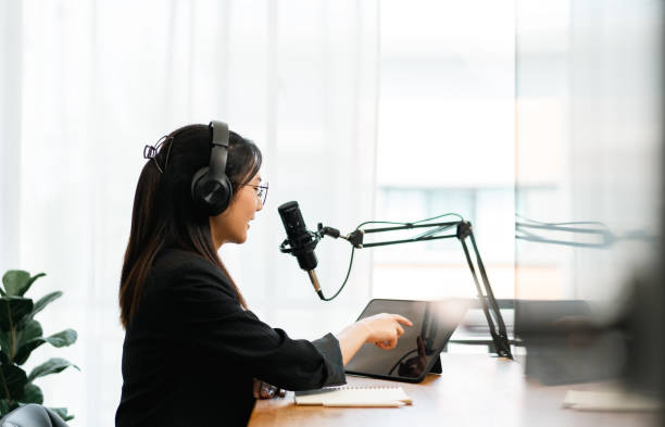 istock Content creator woman host streaming her a podcast with headphones and microphone interview cheering guest conversation at broadcast studio. Blogger motivation recording voice over radio. 1495046039