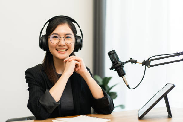istock Content creator woman host streaming her a podcast with headphones and microphone interview cheering guest conversation at broadcast studio. Blogger motivation recording voice over radio. 1495046886