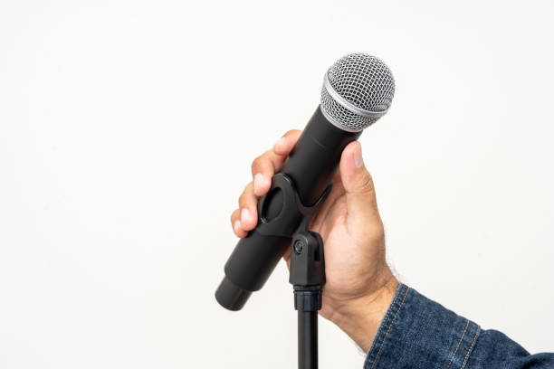 istock Close up male hand holding High quality dynamic microphone and singing song or speaking talking with people on isolated white background. Male testing microphone voice for interview 1495047528