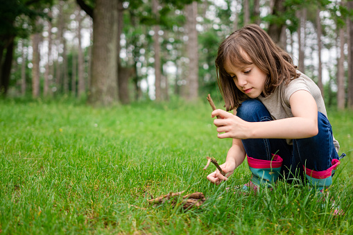 Full length of child girl playing whit branches in the forest