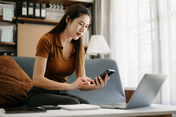 istock Asian businesswoman working in home office with working notepad, tablet and laptop documents  on sofa in living room 1495053002