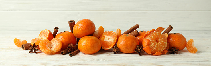 Orange fruit with green leaf in basket on rustic wooden table background.