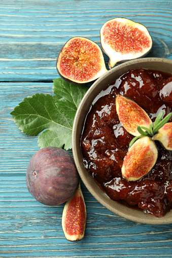 Bowl with fig jam and ingredients on wooden background