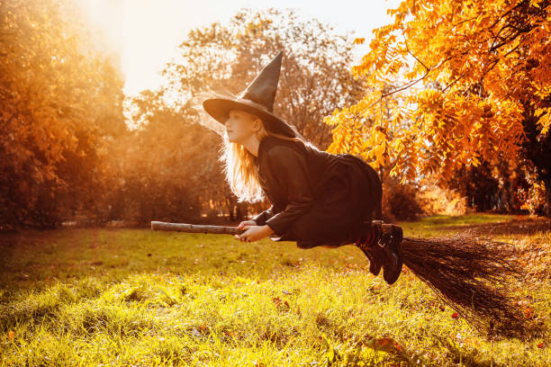 istock A girl in a witch costume sits on a floating broom 1495059497