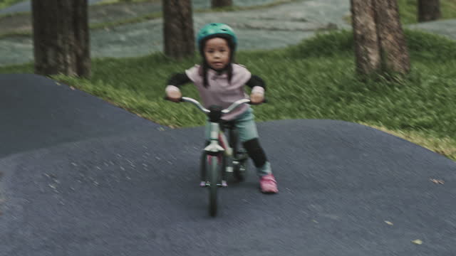Little girl with helmets riding a balance bike