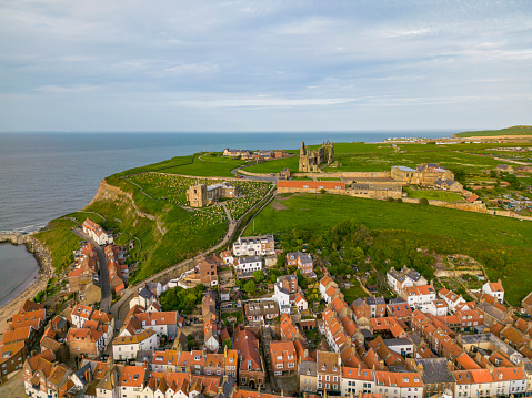 The beautiful coastal town of Whitby in North Yorkshire in England, captured from the air, Whitby Abbey, St Mary's Church and the harbour during golden hour