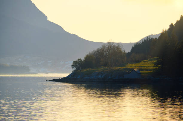 istock Sunset on the fjord with mountains in Norway. Diffuse light, sun rays on a meadow 1495075634