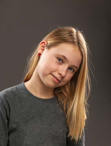 Studio portrait of a beautiful blond teenage girl with long hair and blue eyes isolated against a white background.