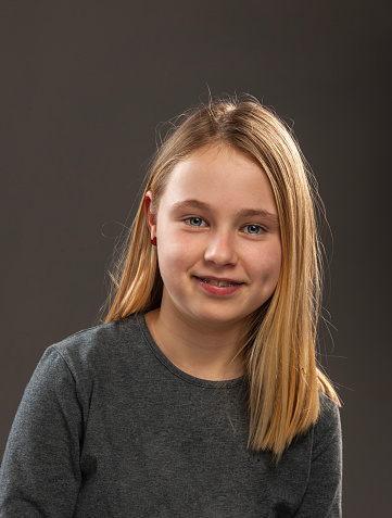 Studio Portrait of a young girl with blue eyes and blond hair. with dental braces