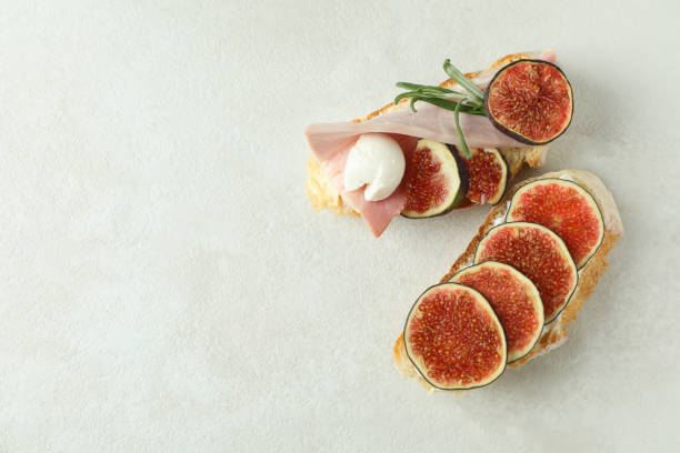 istock Tasty bruschetta with fig on white textured background 1495077746