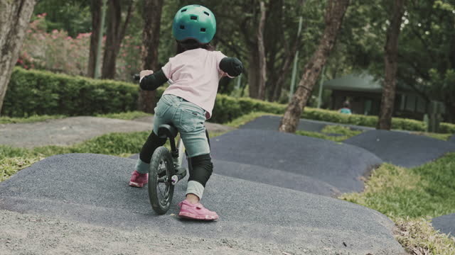 Little girl pedals bike and smiles